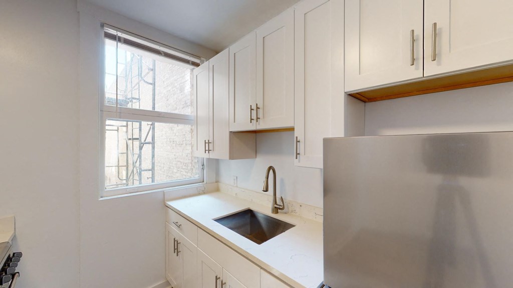 a kitchen with white cabinets and a sink and a refrigerator