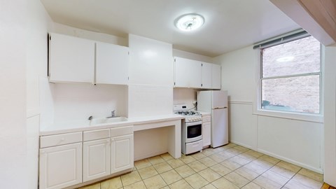 A kitchen with white cabinets and a window.