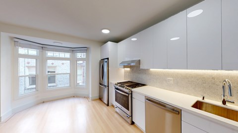 A modern kitchen with white cabinets and stainless steel appliances.