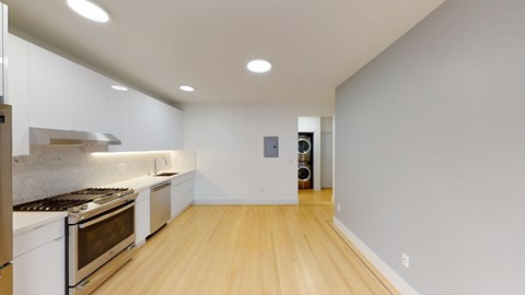 A modern kitchen with wooden floors and stainless steel appliances.