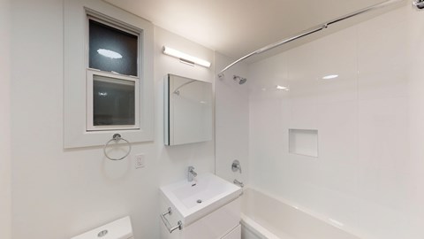 A white bathroom with a toilet, sink, and mirror.