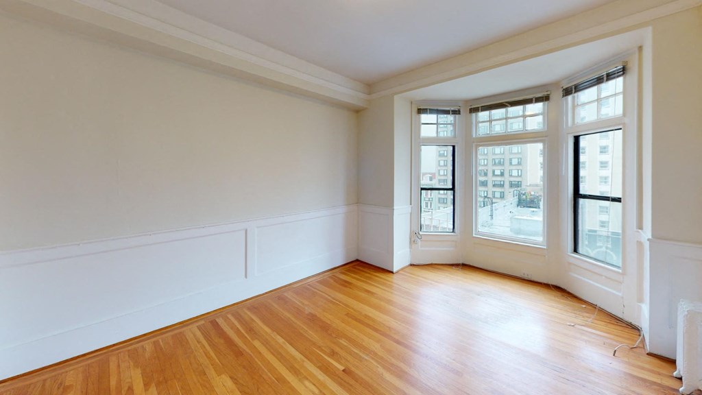 an empty living room with wood floors and windows