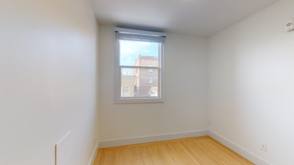 a bedroom with a window and wooden floors