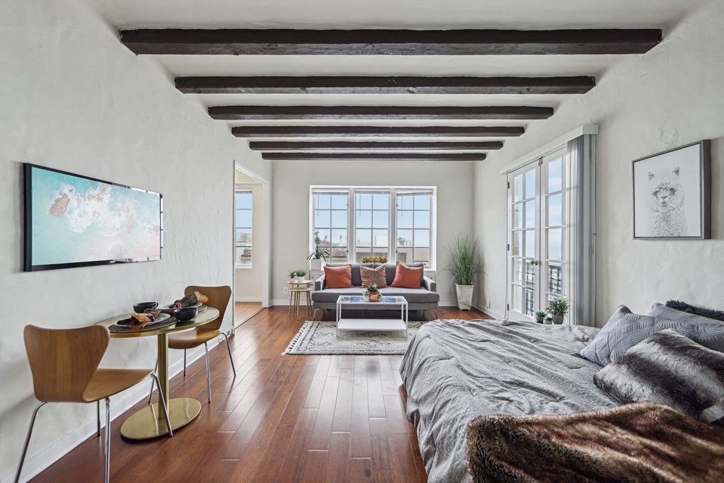 a bedroom with a bed and a couch and a living room with a large window