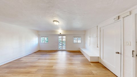 A large empty room with wooden floors and white walls.