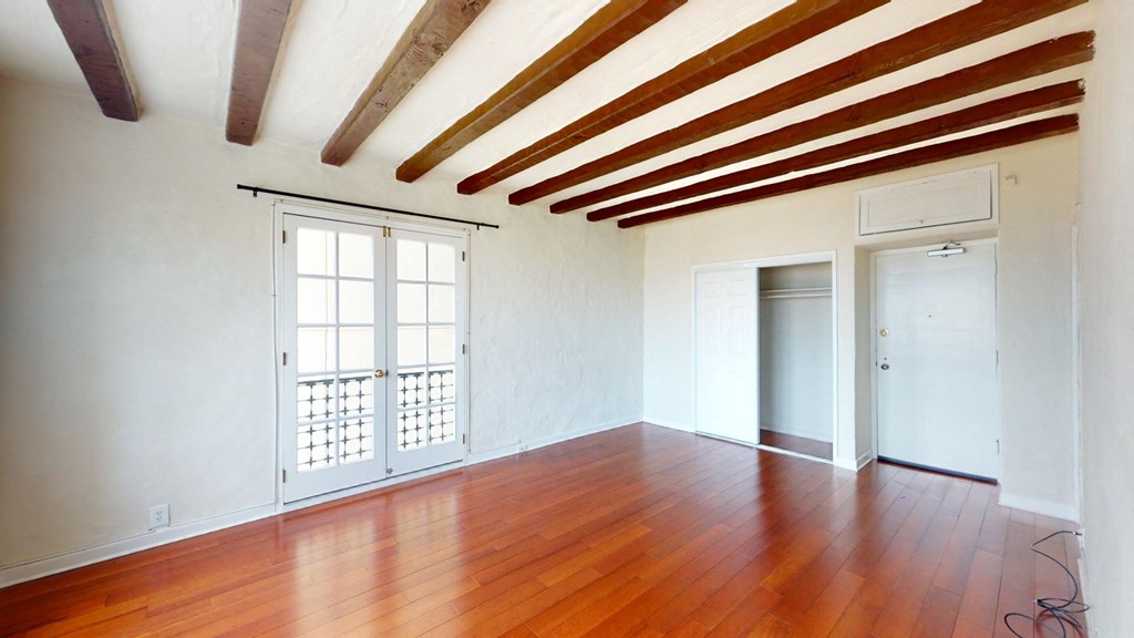 an empty living room with wood floors and white walls