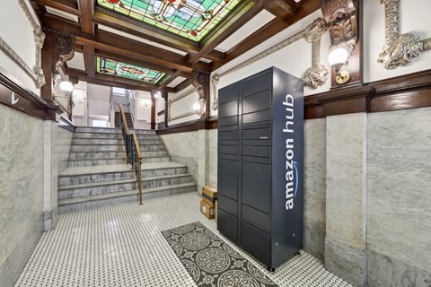 A tall black Amazon Hub lobby unit sits in front of a staircase.