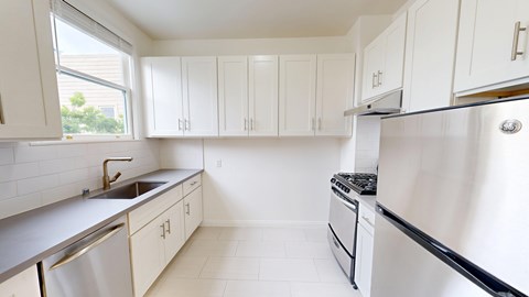 A kitchen with white cabinets and a stainless steel refrigerator.