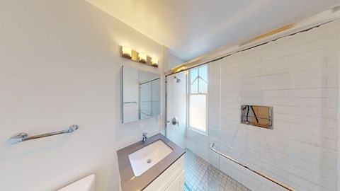 A white bathroom with a sink, mirror, and shower.