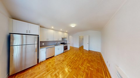 A kitchen with white cabinets and a wooden floor.