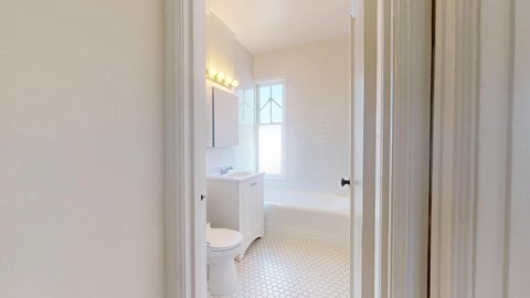 A white bathroom with a toilet, sink, and window.