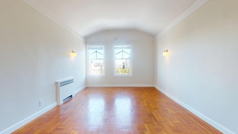 A room with wooden floors and two windows.