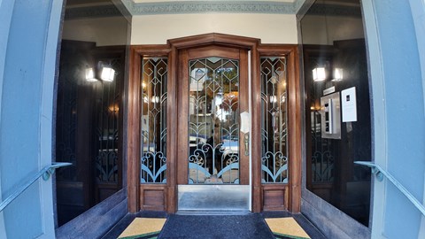 A set of double doors with a glass panel and metal grill work.