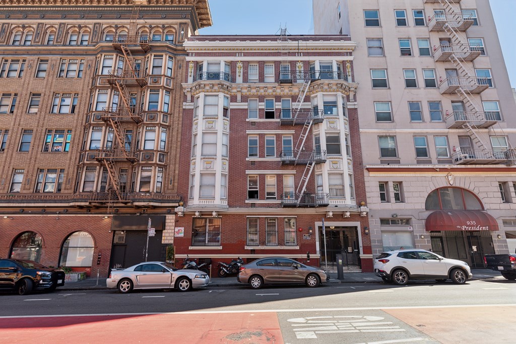 A street view of a city with buildings, cars and a fire escape.