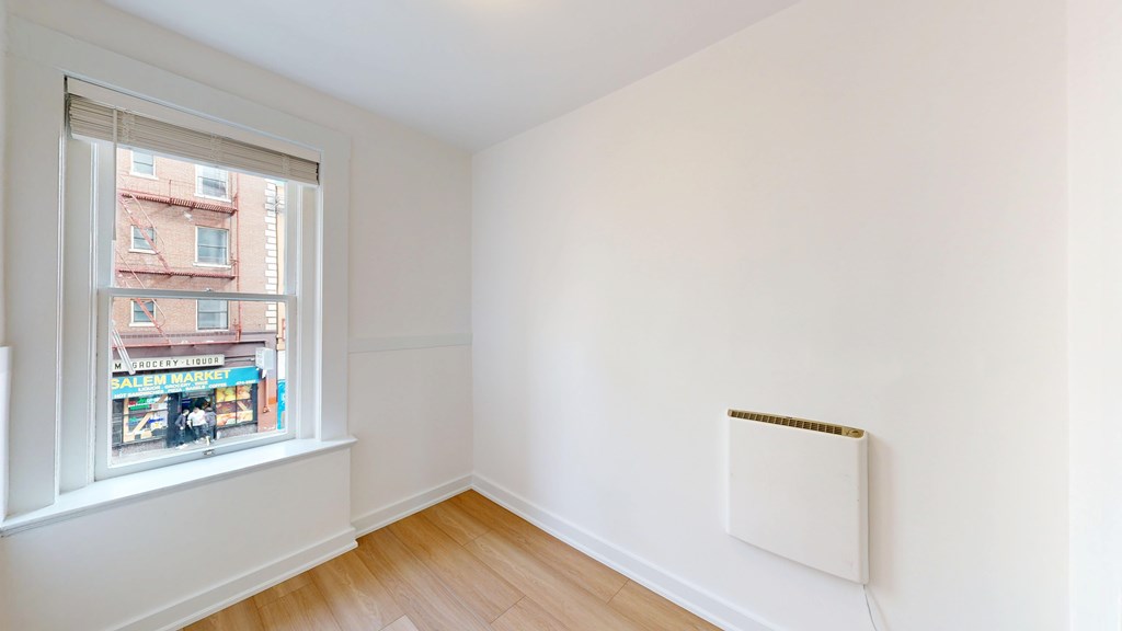 A room with a window and a white wall.