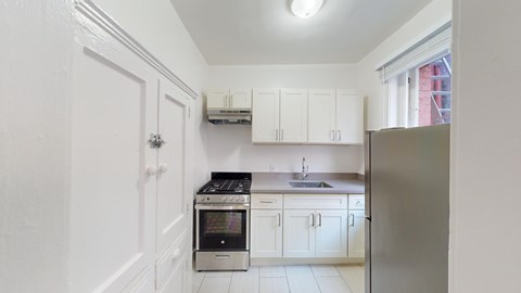 A kitchen with white cabinets and a stainless steel refrigerator.