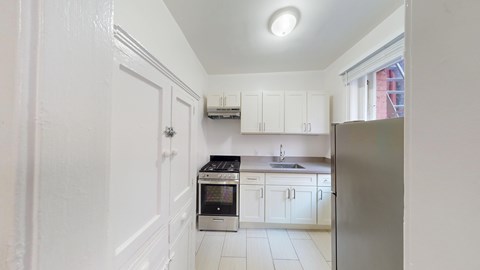 A kitchen with white cabinets and a stainless steel refrigerator.