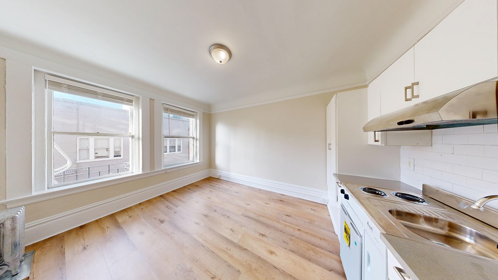 A kitchen with white cabinets and a wooden floor.