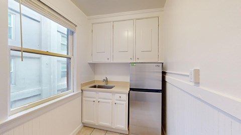 A kitchen with white cabinets and a stainless steel refrigerator.