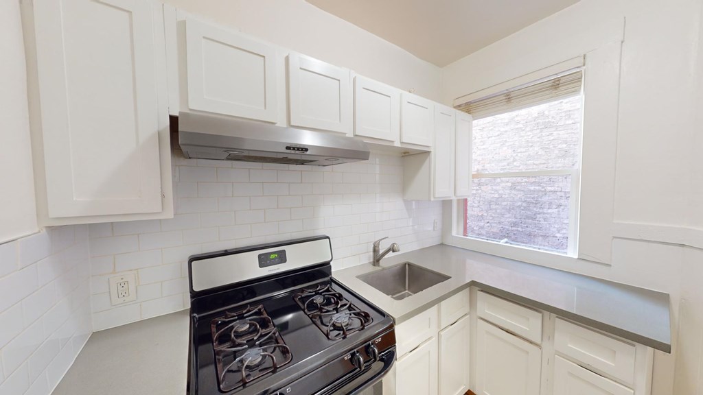 A kitchen with white cabinets and a black stove top oven.