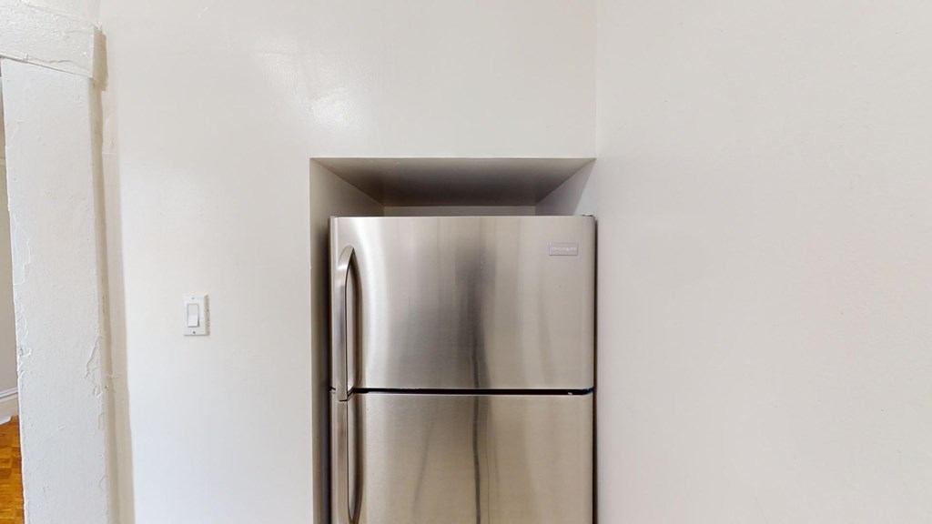 A stainless steel refrigerator in a room with white walls.