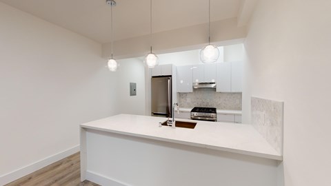 A kitchen with a white countertop and a stainless steel refrigerator.