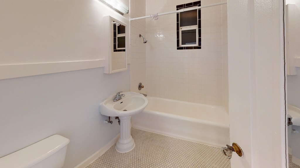 A white bathroom with a toilet, sink, and bathtub.