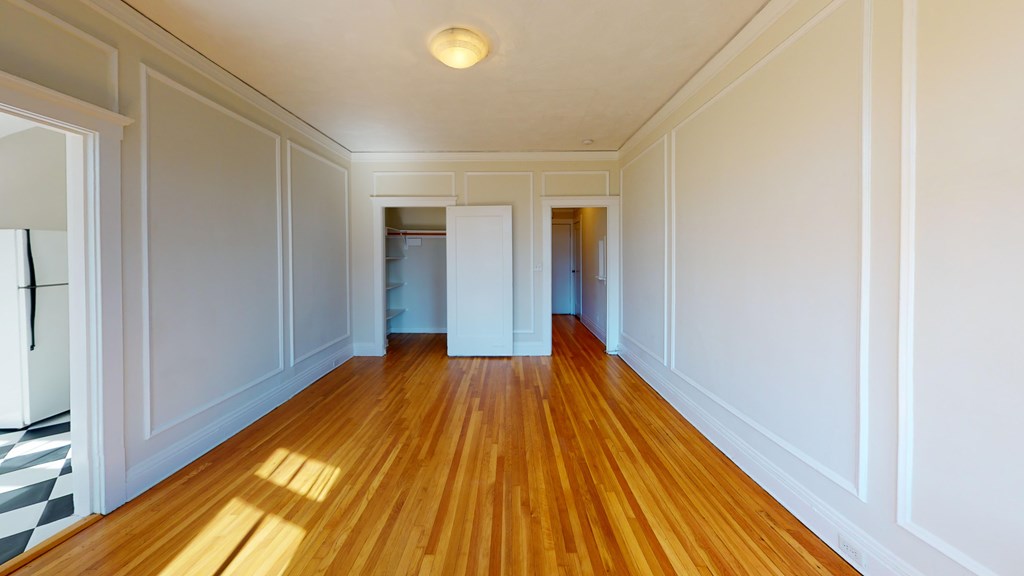 A long hallway with wooden floors and white walls.