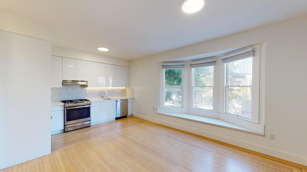 a kitchen with white cabinets and a large window