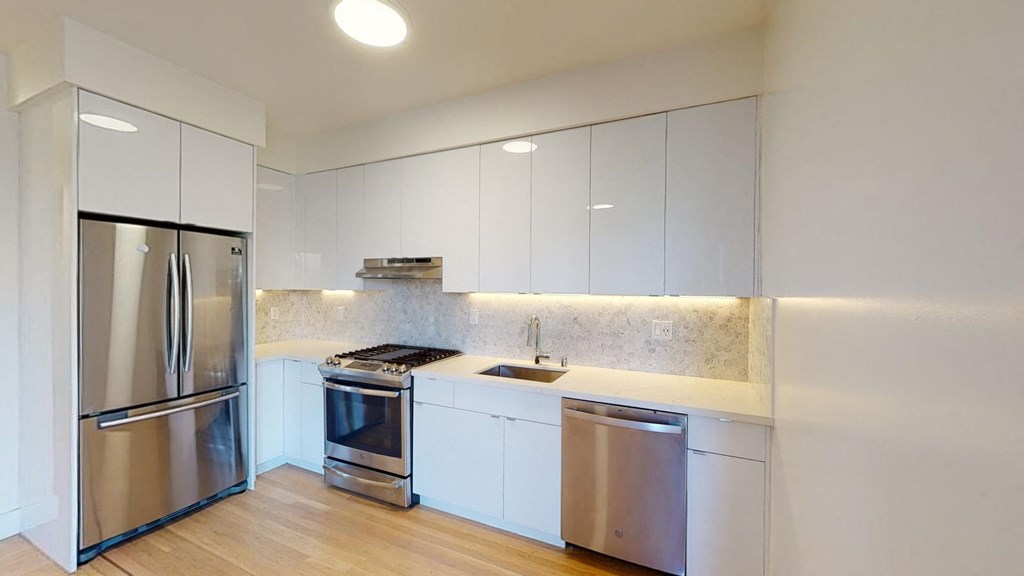 a kitchen with white cabinets and a stainless steel refrigerator