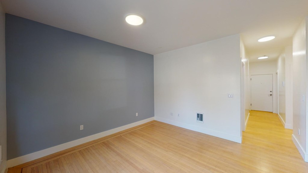 a living room with a hard wood floor and a blue wall