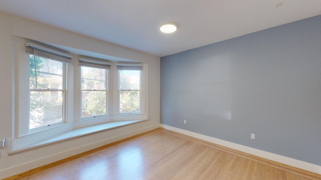 an empty room with three windows and wood floors
