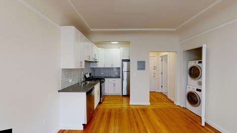 A kitchen with white cabinets and a wooden floor.