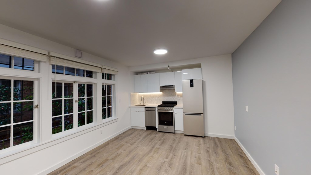 A kitchen with white cabinets and a wooden floor.