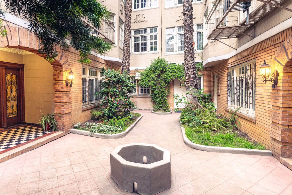 Courtyard with a fountain, surrounded by lush greenery, including palm trees and bushes Courtyard with a fountain, surrounded by lush greenery, including palm trees and bushes