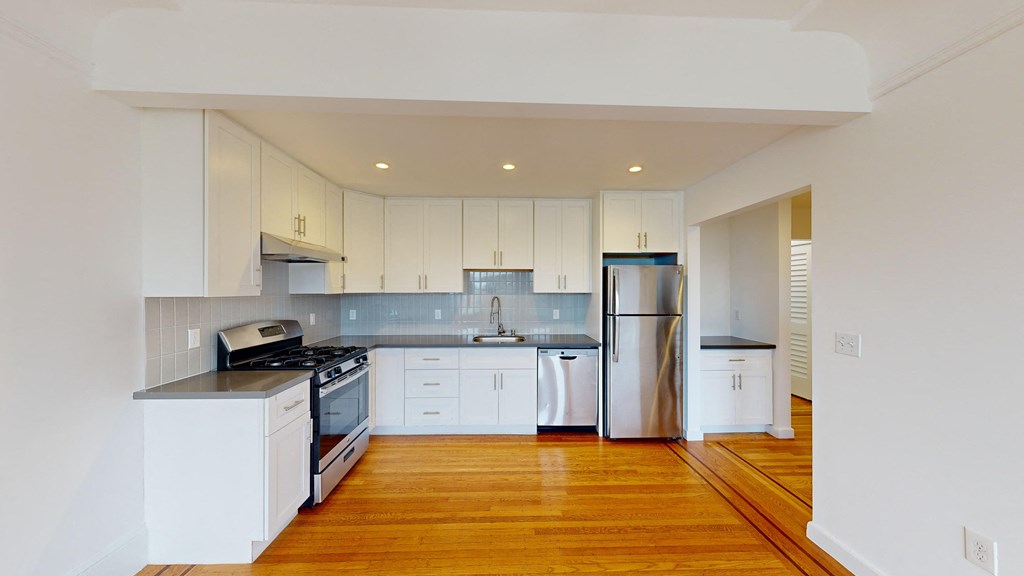 a renovated kitchen with white cabinets and stainless steel appliances