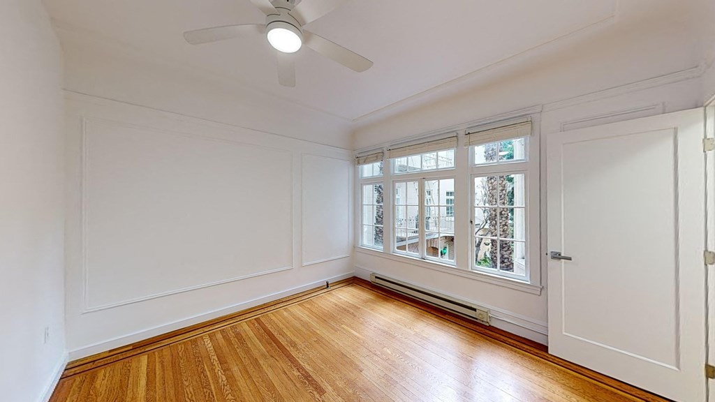 a living room with white walls and a window and wood floors