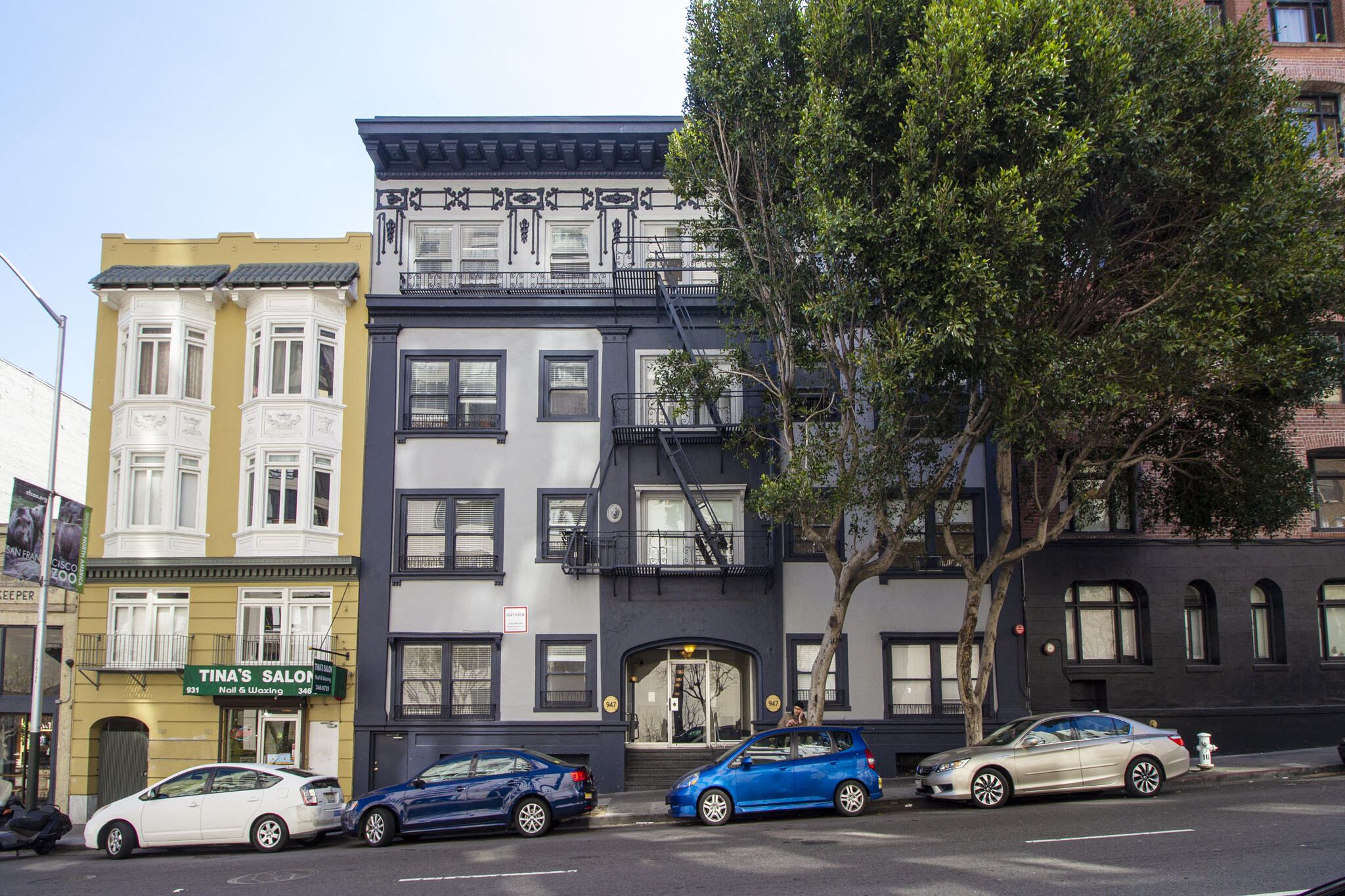 A blue car is parked in front of a building with a sign that says Tina's Salon.