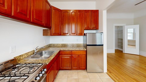A kitchen with wooden cabinets and a stainless steel refrigerator.
