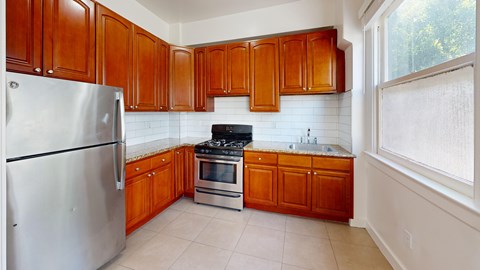 A kitchen with wooden cabinets and a stainless steel refrigerator.