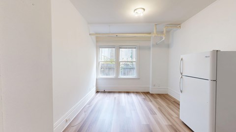 A white refrigerator is in a room with a window.