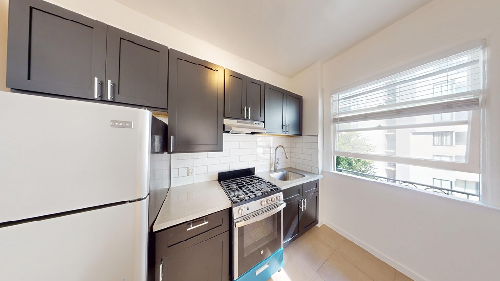 A kitchen with a white fridge and black cabinets.