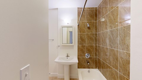 A bathroom with a sink, mirror, and tiled shower.