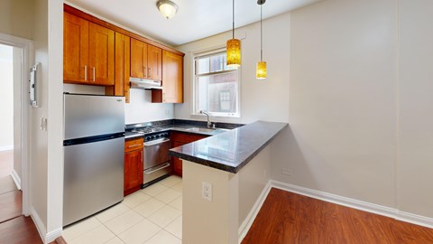 A kitchen with wooden cabinets and a stainless steel refrigerator.
