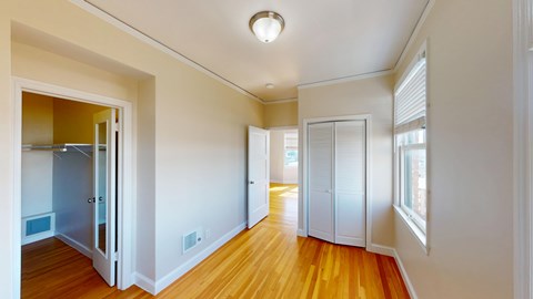 A long hallway with a refrigerator on the left and a door on the right.