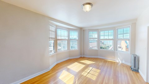 A sunny room with wooden floors and large windows.