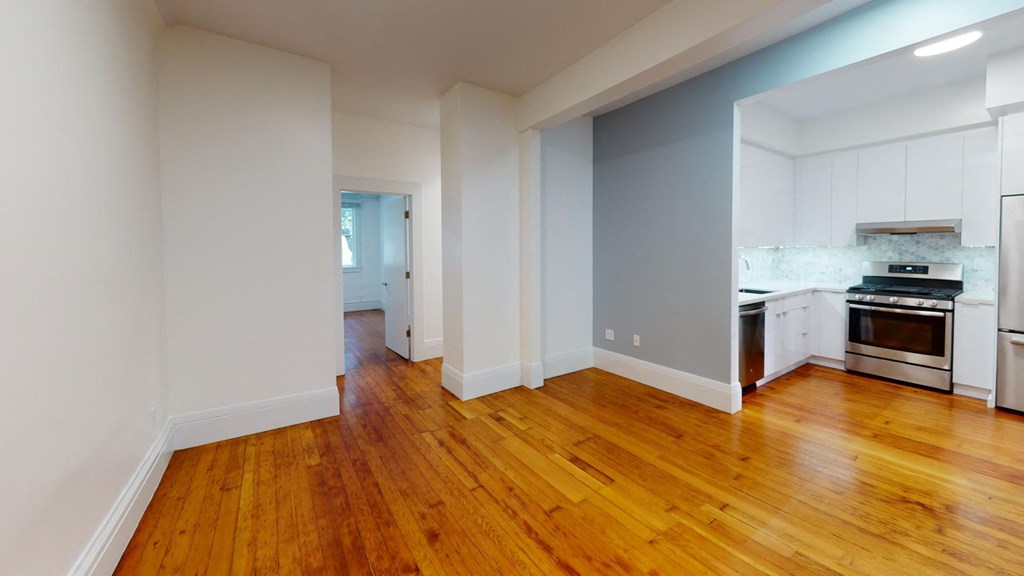a living room and kitchen with wood floors and white cabinets