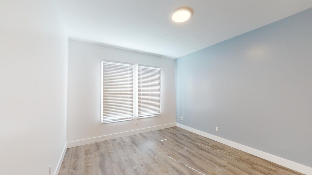 an empty room with white walls and wood floors and a window