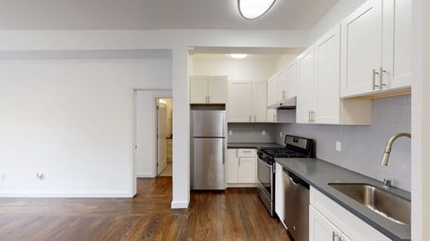 A kitchen with white cabinets and a stainless steel refrigerator.