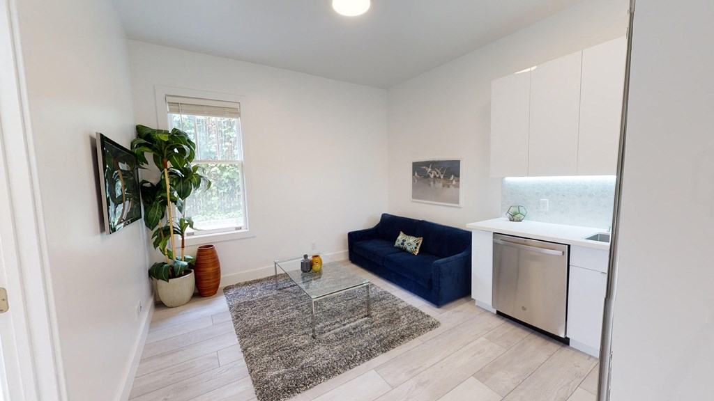 a living room with a blue couch and a kitchen with a sink